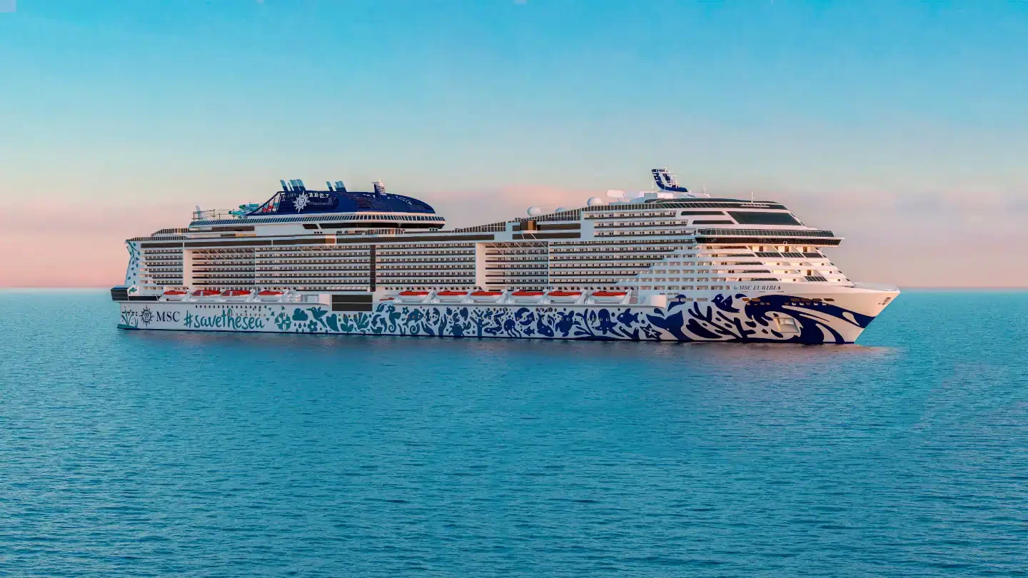 A large white cruise ship with blue floral hull art and the words MSC savethesea sails on calm open water at dusk.