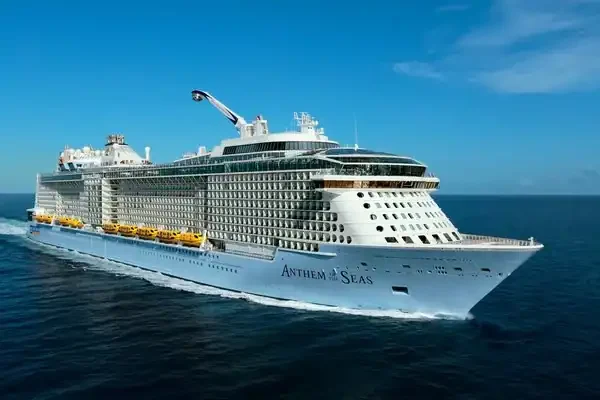 The cruise ship Anthem of the Seas sails through calm blue ocean water under a clear sky.