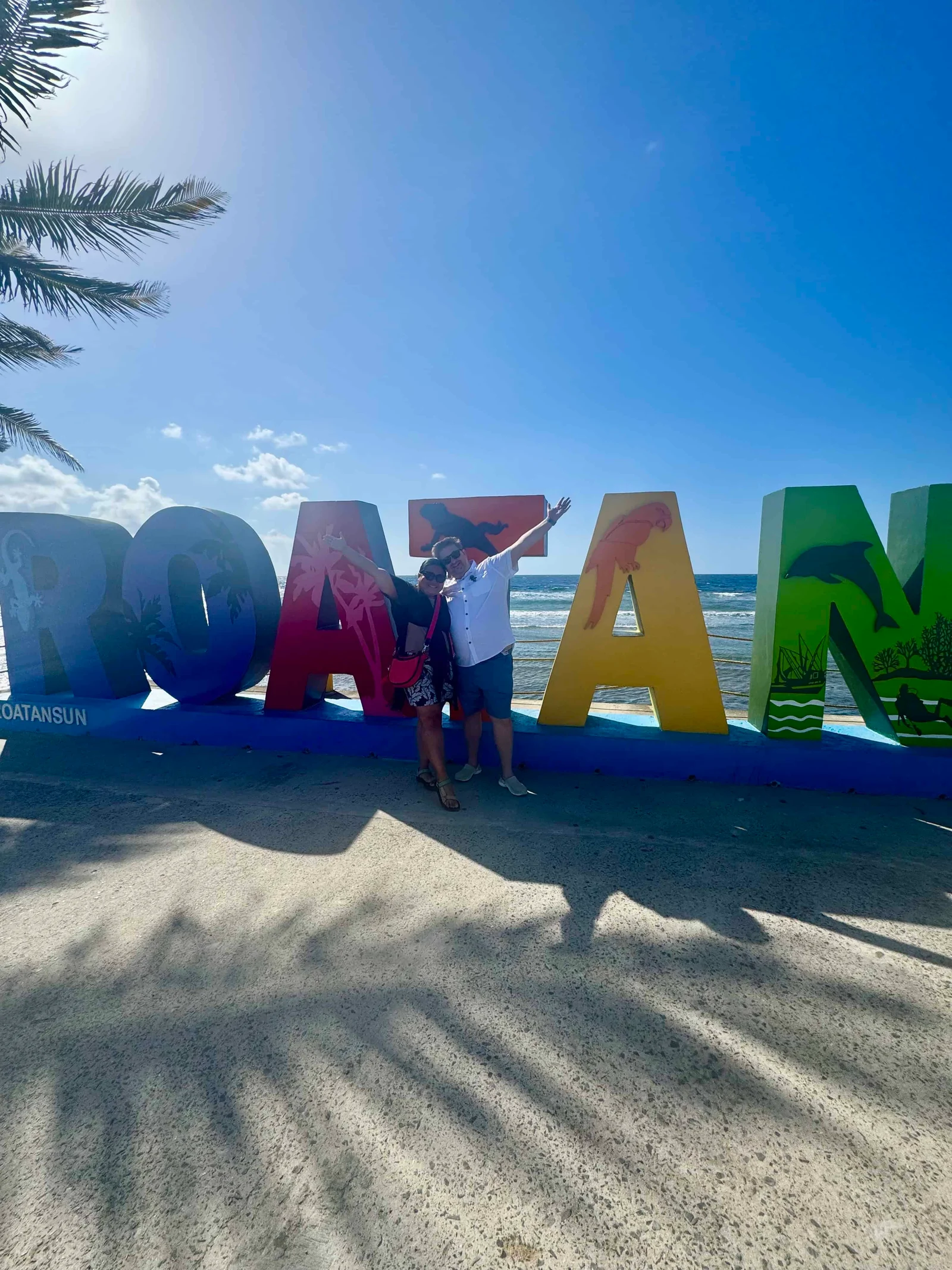 Two people posing with Roatan sign