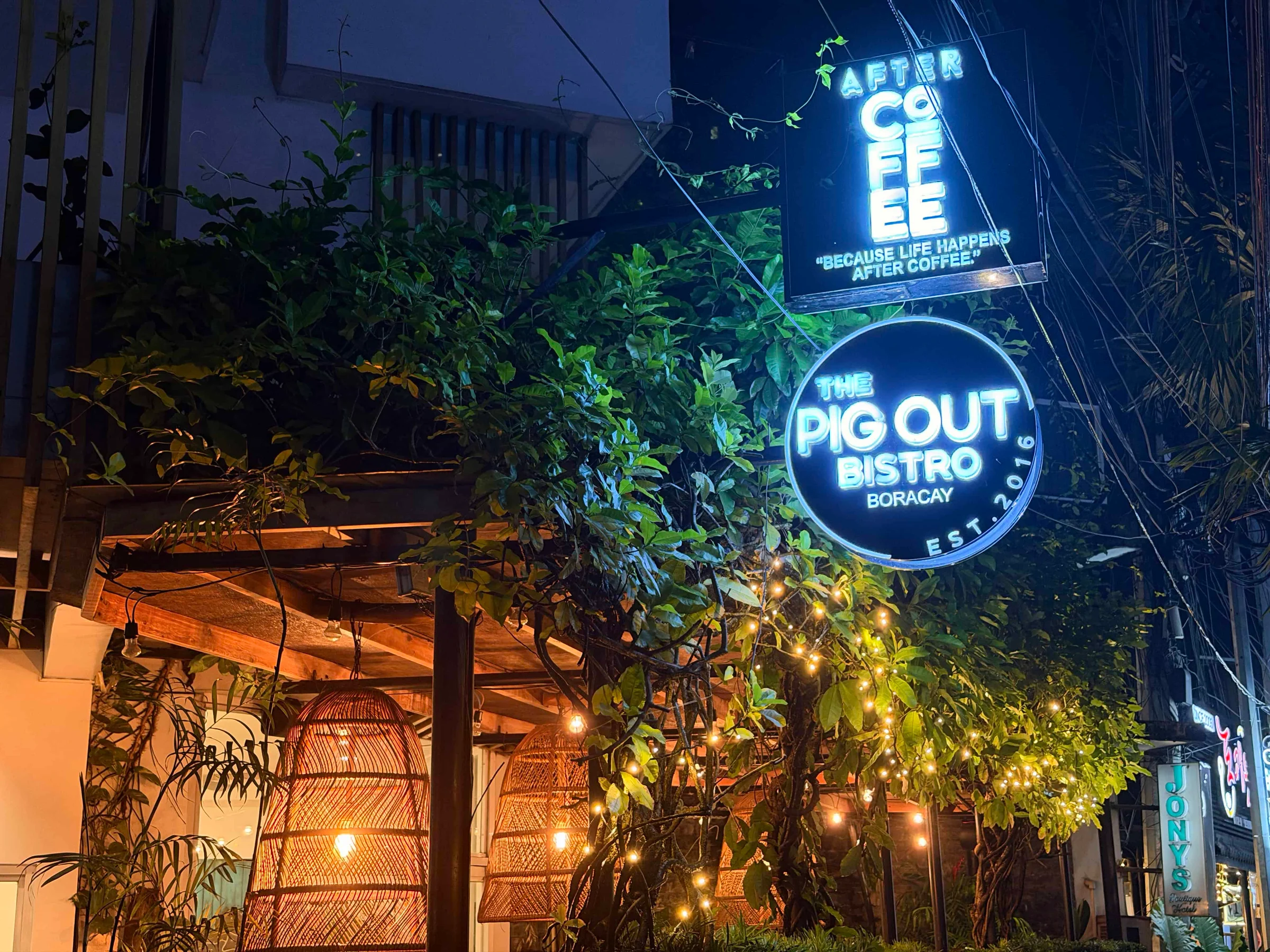Neon signs outside leafy bistro