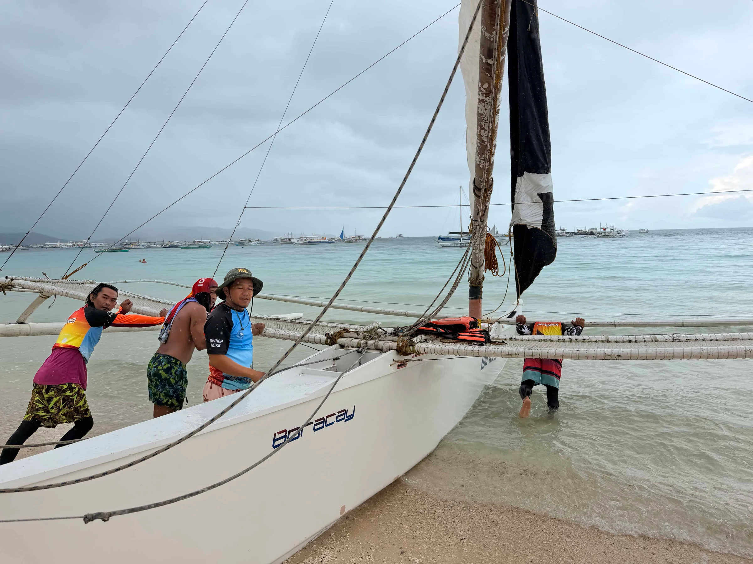 Men pushing sailboat into water