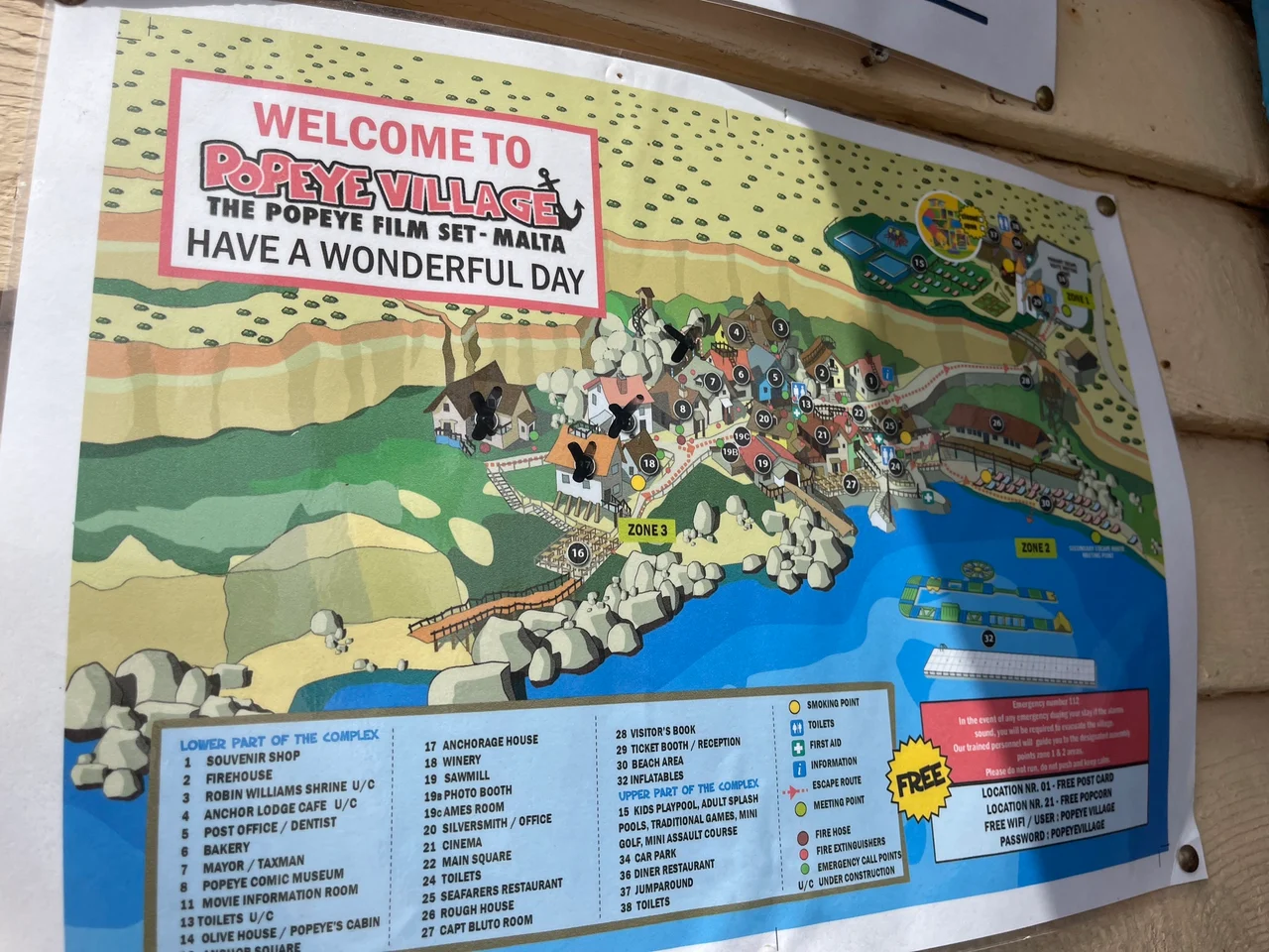 A welcome map sign for Popeye Village, the Popeye film set in Malta, mounted on a wooden wall.