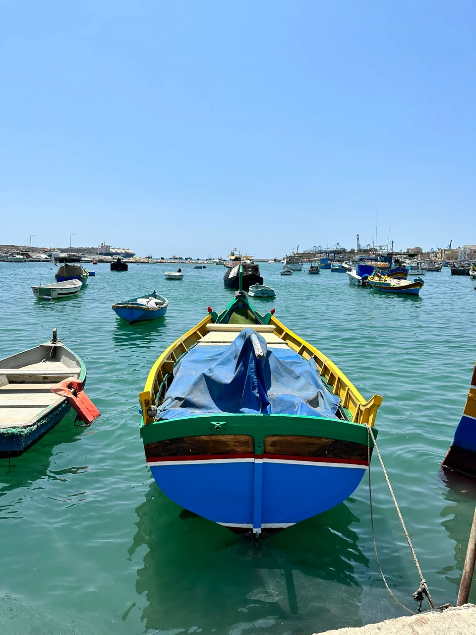 Colourful wooden fishing boats moored on calm turquoise water beneath a clear blue sky.