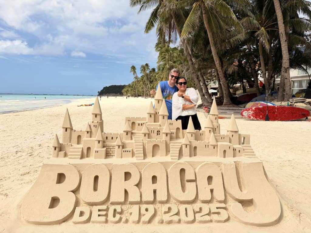 Couple posing behind sandcastle Boracay