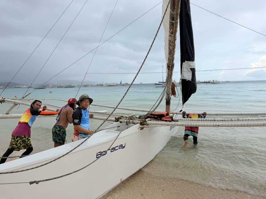 Men pushing sailboat into water