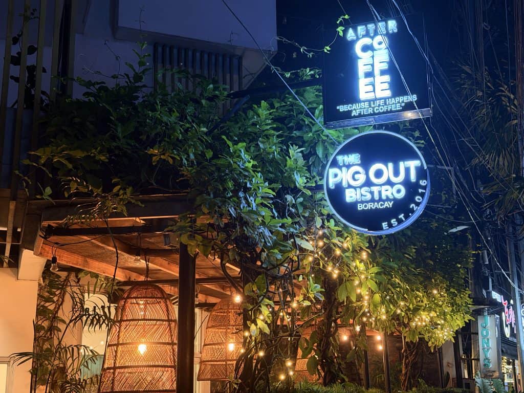 Neon signs outside leafy bistro
