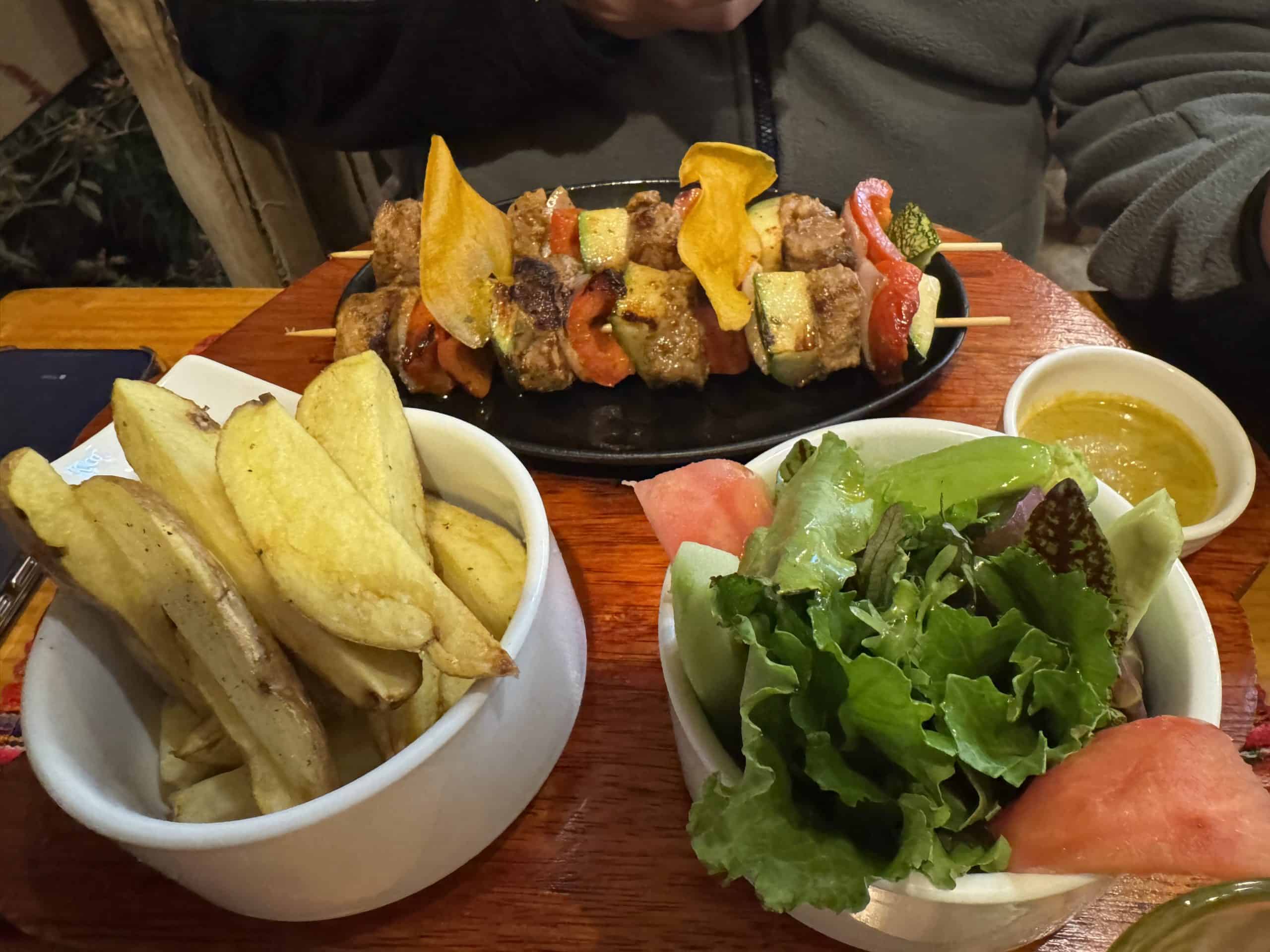 Grilled meat skewers with chips salad