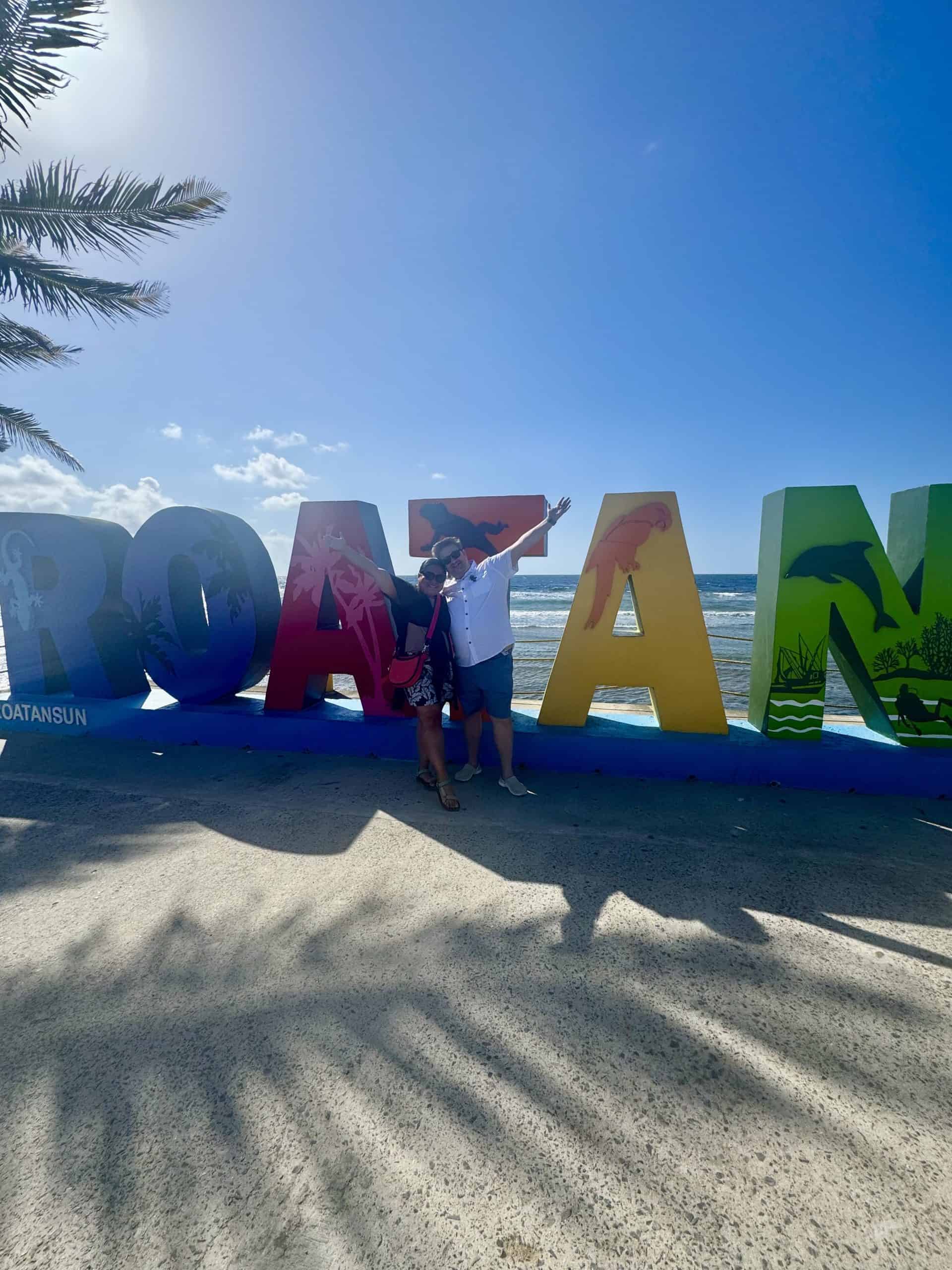 Two people posing with Roatan sign